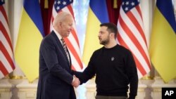 Presiden AS Joe BIden (kiri) menjabat tangan Presiden Ukraina Volodymyr Zelenskyy dalam pertemuan di Kyiv, Ukraina, pada 20 Februari 2023. (Foto: Ukrainian Presidential Press Office via AP)