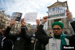 FILE - French Muslim youths hold placards which read, "I am Muslim. I love my Prophet" (R) and "I am Muhammad. I belong to the Muslim community and I am anti-terrorist" during a demonstration in central Paris, Jan. 18, 2015.