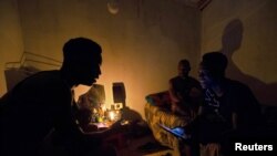 FILE - Friends talk by candlelight during load shedding in Embo, South Africa, March 18, 2019. 
