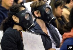 FILE - Protesters wearing gas masks, attend a hearing about a gas leak at the southern California Gas Company's Aliso Canyon Storage Facility near the Porter Ranch section of Los Angeles. The Los Angeles County Department of Public Health released results May 13, 2016, that showed barium, manganese and vanadium were found more frequently and in higher concentrations in homes in the Porter Ranch area.