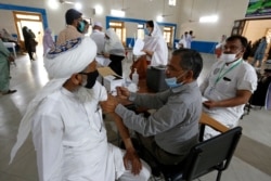 A teacher receives the first shot of the Sinovac coronavirus vaccine from a paramedics in a vaccination center at a school in Lahore, Pakistan, May 28, 2021.