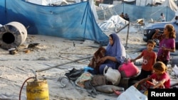 在加沙地带南部汗尤尼斯的 Al-Mawasi 地区，以色列袭击了一个为流离失所者提供庇护的帐篷营地，一名巴勒斯坦妇女在现场翻看儿童身边的物品。（2024年9月10日）