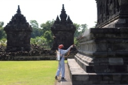 Seorang pekerja menyemprotkan cairan disinfektan di sebuah candi untuk mencegah penyebaran virus corona (Covid-19) di Klaten, Jawa Tengah, 19 Maret 2020. (Foto: Antara via Reuters)