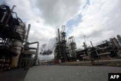 FILE - Thick black smoke billows from a pencil-thin chimney at the Port Harcourt Refining Company Limited, Rivers State on Sept. 16, 2015.
