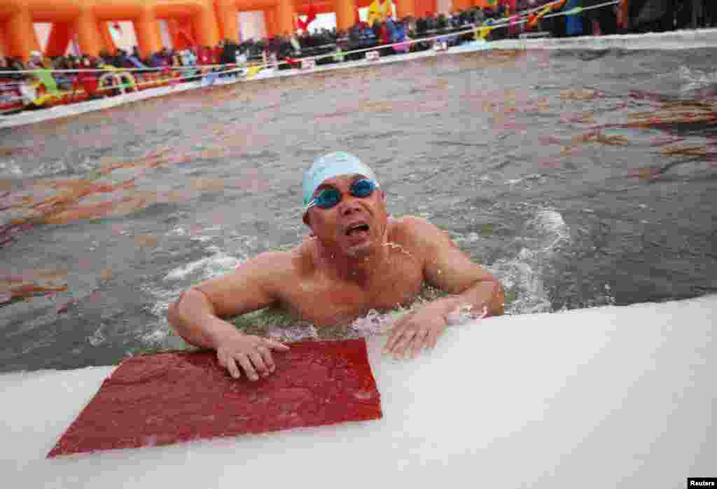 Seorang perenang menyelesaikan lomba renang di sungai Songhua yang dingin membeku, dalam kompetisi renang musim dingin di kota Harbin, Heilongjiang, China.