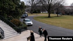 U.S. First Lady Jill Biden guides one of the family dogs, Champ, on his arrival at the White House