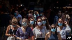 Tourists wearing face masks wait to cross a road in downtown Barcelona, Spain, July 16, 2020.