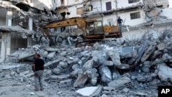 Workers remove the rubble of a building destroyed by an Israeli airstrike, in Gaza City, Tuesday, June 15, 2021. The building was damaged last month during an 11-day war between Israel and the Hamas militant group that rules Gaza. (AP Photo/Adel…