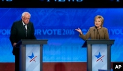 FILE - Bernie Sanders, left, listens as Hillary Clinton speaks during a Democratic presidential primary debate at Saint Anselm College in Manchester, N.H., Dec. 19, 2015.