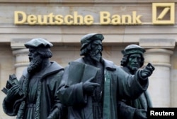 FILE - A statue stands next to the logo of Germany's Deutsche Bank in Frankfurt, Germany, Sept. 30, 2016.