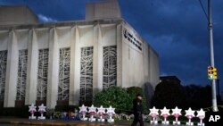 A Pittsburgh Police officer walks past the Tree of Life Synagogue on Sunday, Oct. 28, 2018, the site of a shooting that killed 11 people. (AP Photo/Gene J. Puskar)