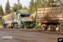 FILE - This image provided by the Syrian anti-government group Aleppo 24 news, shows damaged trucks carrying aid, in Aleppo, Syria, Sept. 20, 2016.