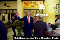 U.S. Secretary of State John Kerry waves to tourists after he entered the famed Foreign Correspondents Club in Phnom Pehn, Cambodia, Jan. 25, 2016.