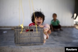 FILE - A Syrian refugee child reacts while sitting in a swing in Al Zaatari refugee camp, in the Jordanian city of Mafraq, near the border with Syria, September 19, 2015.