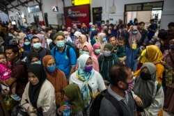 Para penumpang kereta api mengenakan masker sebagai pencegahan virus corona, di stasiun di Surabaya, 15 Maret 2020. (Foto: AFP)