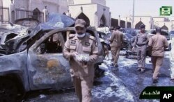FILE - In this image taken from video provided by Saudi TV, burned-out cars are seen as investigators collect evidence in the aftermath of a suicide bomb outside the Imam Hussein mosque in the port city of Dammam, Saudi Arabia, May 29, 2015. The Islamic State group said one of its soldiers had carried out the attack.