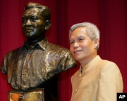 FILE - Sombath Somphone of Laos, the winner of Ramon Magsaysay Award for Community Leadership in 2005, poses with the bust of the late Philippine president, Aug. 31, 2005.