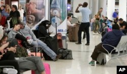 Travelers wait near a closed terminal at the Miami International Airport., Jan. 12, 2019. The partial government shutdown is starting to strain the national aviation system, with unpaid security screeners staying home, air traffic controllers suing the government and safety inspectors off the job.