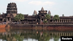Tourists walk along the outer wall of Angkor Wat, reflected in its moat in Siem Reap, December 9, 2007.