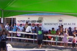 In this November 2019, image from video, children with parents wait in line to get vaccinated outside a health clinic in Apia, Samoa.