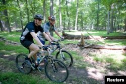 FILE - U.S. President George W. Bush and Danish Prime Minister Anders Fogh Rasmussen (left) navigate a path at Camp David presidential retreat, on mountain bikes, June 9, 2006.