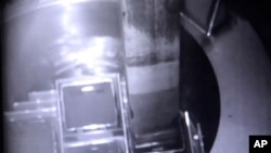 In this image released by Tokyo Electric Power Co. (TEPCO), a fuel is placed into a protective cask inside a cooling pool at Unit 3 to be transported to another storage site at the Fukushima nuclear plant in Okuma town, Fukushima prefecture.