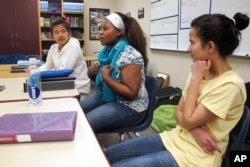 FILE - Nakafu Kahasha, center, describes her short story about her journey from Congo to Tanzania to Fargo, N.D., nearly six years ago, while Nepal natives Anju Tamang, left, and Anju Gurung listen during their English-language learners class at Fargo South High School, Jan. 26, 2016.