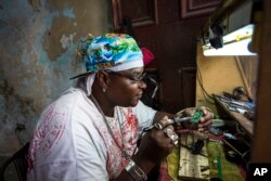 Private jeweler and electronics technician Gabriel La O repairs a mobile phone inside a government store where he rents work space in Havana, May 24, 2016. Cuba says it will legalize small and medium-sized private businesses.