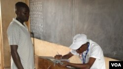 Election official checks voter credentials on election day in Bujumbura, Burujdi, June 29, 2015. (Photo: Edward Rwema / VOA)