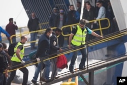 Officers from the European Union’s border protection agency, Frontex, lead a migrant as they get in a ferry in the port of Mytilini, Lesbos island , Greece, April 8, 2016.