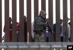 A U.S. Customs and Border Protection officer walks along a wall at the border between Mexico and the United States, as seen from San Diego, California, Nov. 25, 2018.