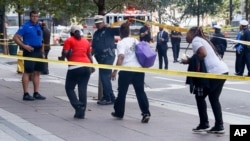 Pedestrians are allowed to exit police cordons as emergency personnel and police work the scene of shooting near Fountain Square, Sept. 6, 2018, in downtown Cincinnati.