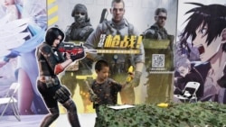 A child plays with a toy gun during a promotion for online games in Beijing on Saturday, Aug. 29, 2020. (AP Photo/Ng Han Guan)