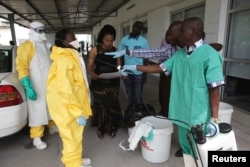 FILE - A health worker sprays a colleague with disinfectant during a training session for Congolese health workers to deal with Ebola virus in Kinshasa, Oct. 21, 2014.