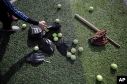 A Palestinian woman choses equipment before starting to train for an all-women's baseball game on a soccer field in Khan Younis, southern Gaza Strip, March 19, 2017.