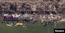 FILE - Police and rescue workers stand near a building which was destroyed in a massive explosion at a fertilizer plant in the town of West, near Waco, Texas, April 18, 2013.
