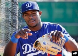 FILE - Los Angeles Dodgers' Yasiel Puig talks with a teammate during a spring training baseball workout, in Glendale, Ariz., Feb. 26, 2016.