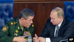 Russian President Vladimir Putin, right, speaks with Chief of the General Staff of the Russian Armed Forces Valery Gerasimov at a meeting with top military officials in the National Defense Control Center in Moscow, Russia, Dec. 11, 2015.