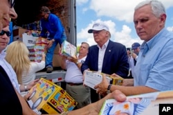Republican presidential candidate Donald Trump and his running mate, Indiana Gov. Mike Pence, right, help to unload supplies for flood victims during a tour of the flood damaged area in Gonzales, Louisiana, Aug. 19, 2016.