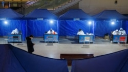 身穿防护服的工作人员在湖北武汉的一个火车站设立旅客登记处。(2021年1月13日)