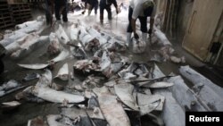 Workers cut off fins from frozen carcasses of a sharks at a fish processing plant in Kaohsiung, southern Taiwan, November 15, 2011.