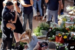 Italian Premier Matteo Renzi, left, comforts a woman at the end of the state funeral service for some of the victims of the earthquake that hit central Italy last Wednesday, in Ascoli Piceno, Italy, Aug. 27, 2016.