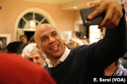 Senator Cory Booker of New Jersey takes selfies with voters at a New Hampshire house party.