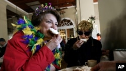 Dressed for Mardi Gras, friends enjoy beignets and coffee at the famous Cafe Du Monde in New Orleans.