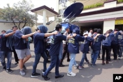 FILE - Police officers escort men arrested in a raid on a gay sauna at North Jakarta police headquarters in Jakarta, Indonesia, May 22, 2017.