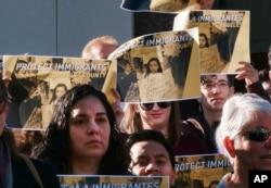 FILE - Holding signs that read "Protect Immigrants," pro-immigration demonstrators stand on the steps of the Kenneth Hahn Hall of Administration in downtown Los Angeles, California, Dec. 20, 2016.
