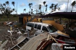 A car is still partially buried under the remains of a building in Humacao, Jan. 25, 2018.