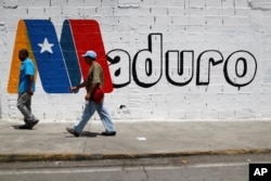 Supporters of Venezuela's President Nicolas Maduro walk past a campaign mural before a rally with him, in Charallave, Venezuela, May 15, 2018.