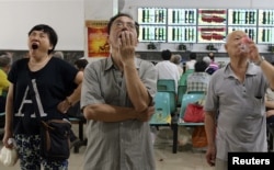 在武汉的证券交易市场，股民们看着电脑屏幕上的股市行情（2015年7月3日）