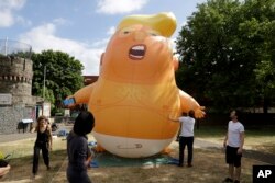 In this July 10, 2018, photo, a six-meter high cartoon baby blimp of U.S. President Donald Trump stands inflated during a practice session in Bingfield Park, north London.